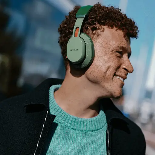 Person wearing Fairphone green headphones outdoors, smiling.